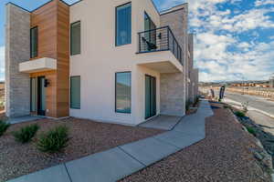 View of front of home with a balcony, stucco siding, and stone siding