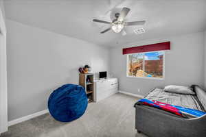 Bedroom featuring light carpet, ceiling fan, and a textured ceiling