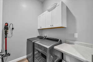 Laundry area featuring cabinet space, washer and dryer, and light wood-style flooring