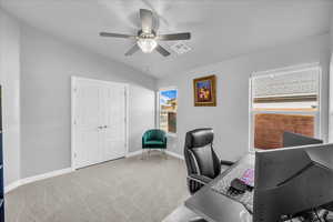 Home office featuring light colored carpet, vaulted ceiling, and a ceiling fan
