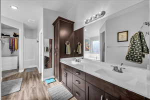 Full bath featuring a spacious closet, double vanity, light wood-style floors, and recessed lighting
