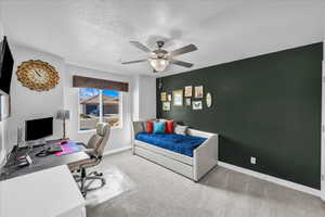 Bedroom featuring carpet floors, an office area, a textured ceiling, and a ceiling fan