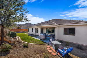 Rear view of property featuring a patio, stucco siding, and a tiled roof
