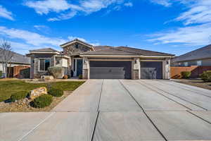 Prairie-style home with stone siding, an attached garage, concrete driveway, a tiled roof, and stucco siding