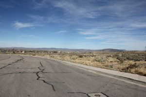 View of asphalt road featuring sidewalks, a view of countryside, and a mountain view