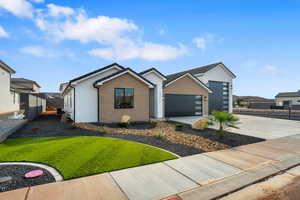 View of front of home with brick siding, concrete driveway, a garage, and stucco siding