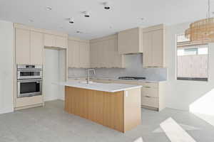 Kitchen featuring cream cabinetry, stainless steel appliances, an island with sink, and recessed lighting