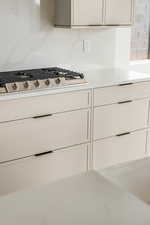 Kitchen view of light countertops, stainless steel gas stovetop, and white cabinetry