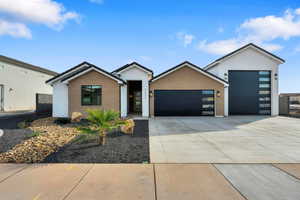 View of front of home featuring brick siding, concrete driveway, a garage, and stucco siding