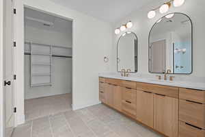 Bathroom featuring a walk in closet and double vanity