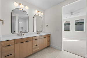 Full bath featuring double vanity, light colored carpet, light tile patterned flooring, and ceiling fan
