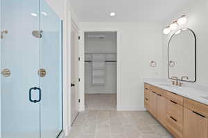 Full bathroom featuring a spacious closet, a stall shower, double vanity, recessed lighting, and light tile patterned floors