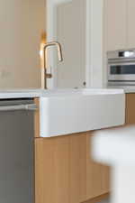 Kitchen view of oven, modern cabinets, stainless steel dishwasher, and light countertops