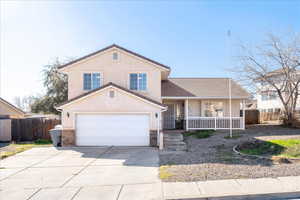 Traditional home featuring a porch, driveway, stucco siding, and a garage
