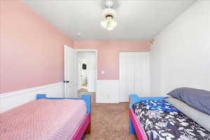 Bedroom with a closet, carpet floors, and a wainscoted wall