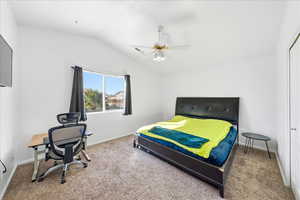Bedroom with vaulted ceiling, ceiling fan, carpet floors, and a desk