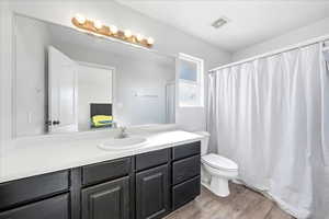 Ensuite bathroom featuring vanity, a shower with shower curtain, and dark wood finished floors