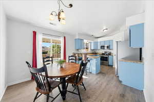 Dining space featuring light wood-style floors, a chandelier, and lofted ceiling