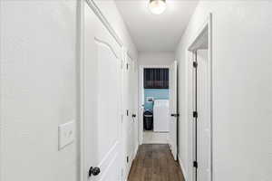Hall with a textured wall, washer / dryer, and dark wood finished floors