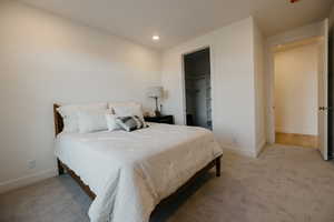 Bedroom featuring a spacious closet, light colored carpet, and recessed lighting
