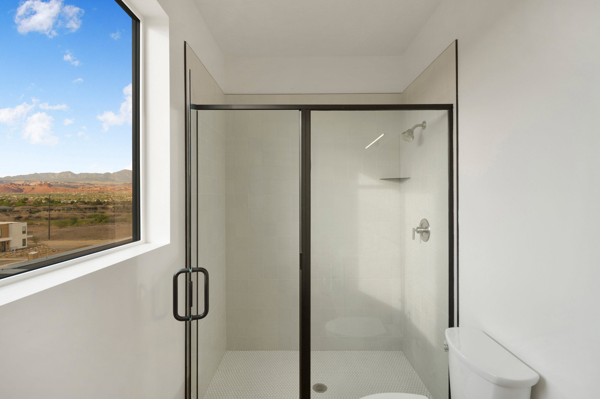 Modern shower enclosure with black-framed glass, white subway tile surround, and hexagonal tile flooring