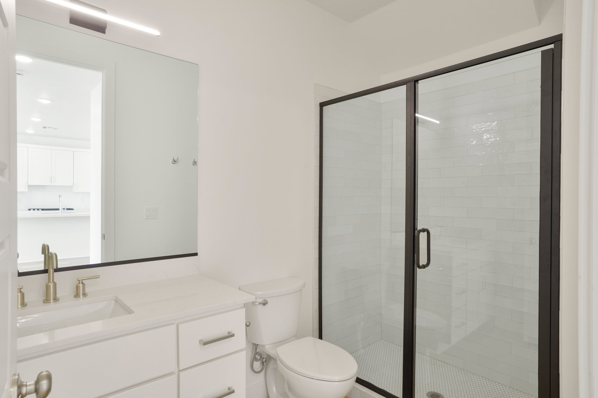 Bathroom featuring a glass-enclosed shower with black framing, white subway tile surround, and mosaic tile flooring