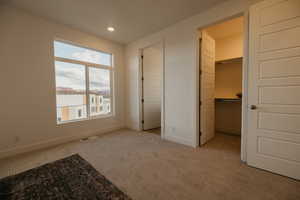 Unfurnished bedroom featuring light colored carpet, a spacious closet, and recessed lighting