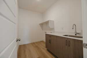 Laundry room featuring light wood-style floors, cabinet space, and washer hookup