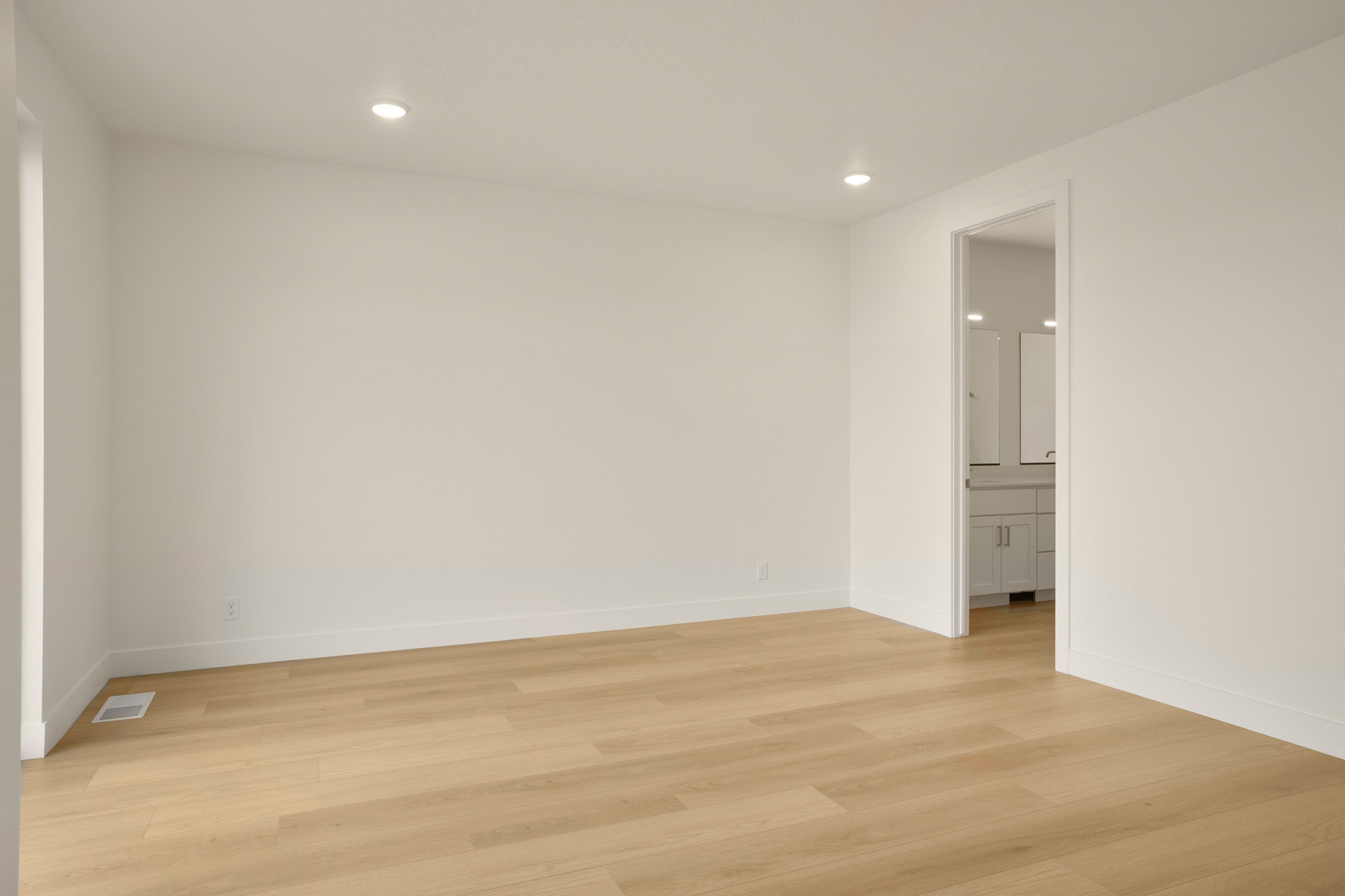 Spacious room with wood-finish flooring, recessed lighting, and white baseboards