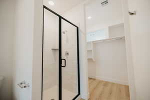 Full bathroom with a stall shower, light wood finished floors, a walk in closet, and recessed lighting