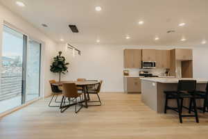 Kitchen with hanging light fixtures, light wood-type flooring, a breakfast bar, recessed lighting, and modern cabinets