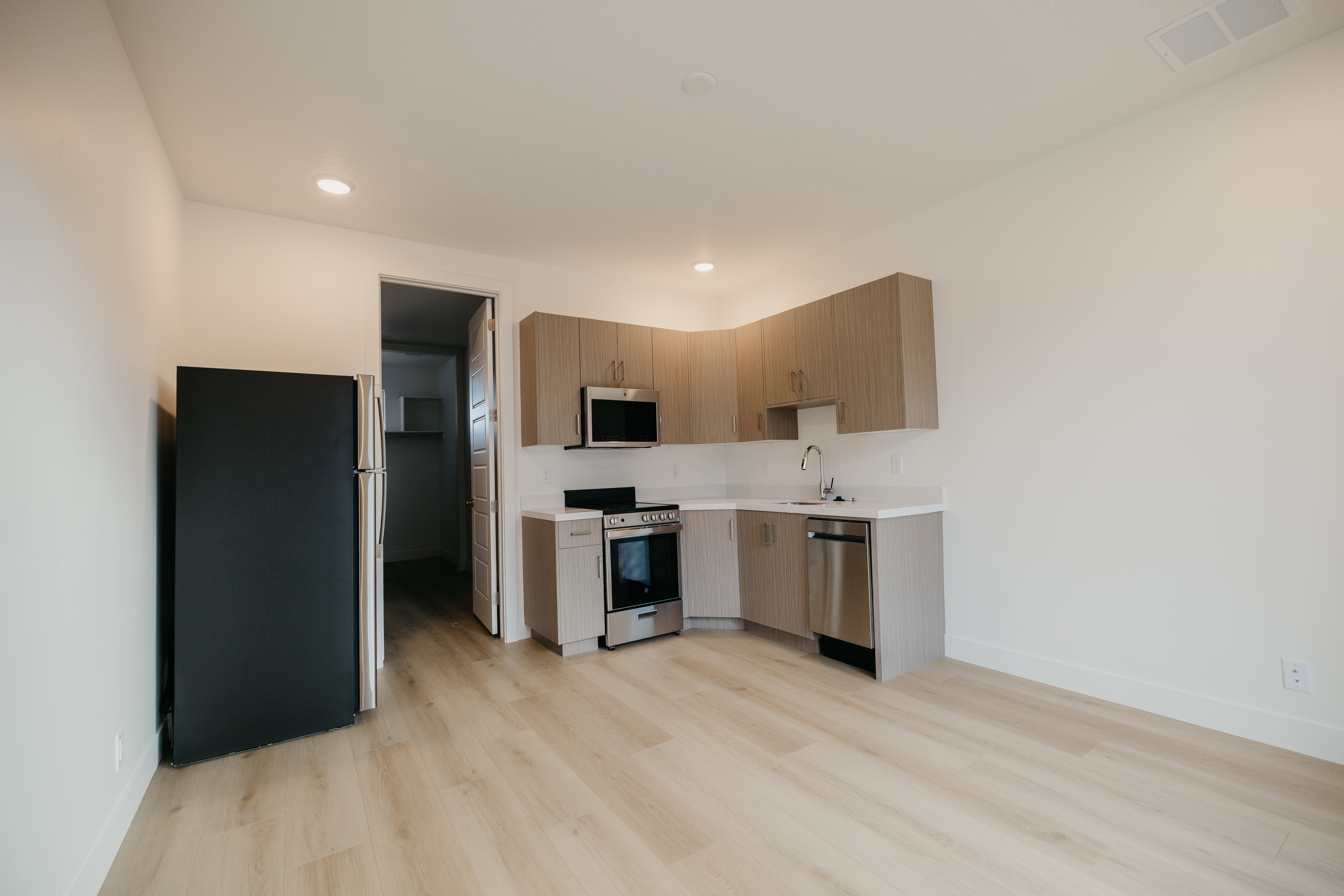 Kitchen with stainless steel appliances, modern cabinets, light wood finished floors, recessed lighting, and light brown cabinets