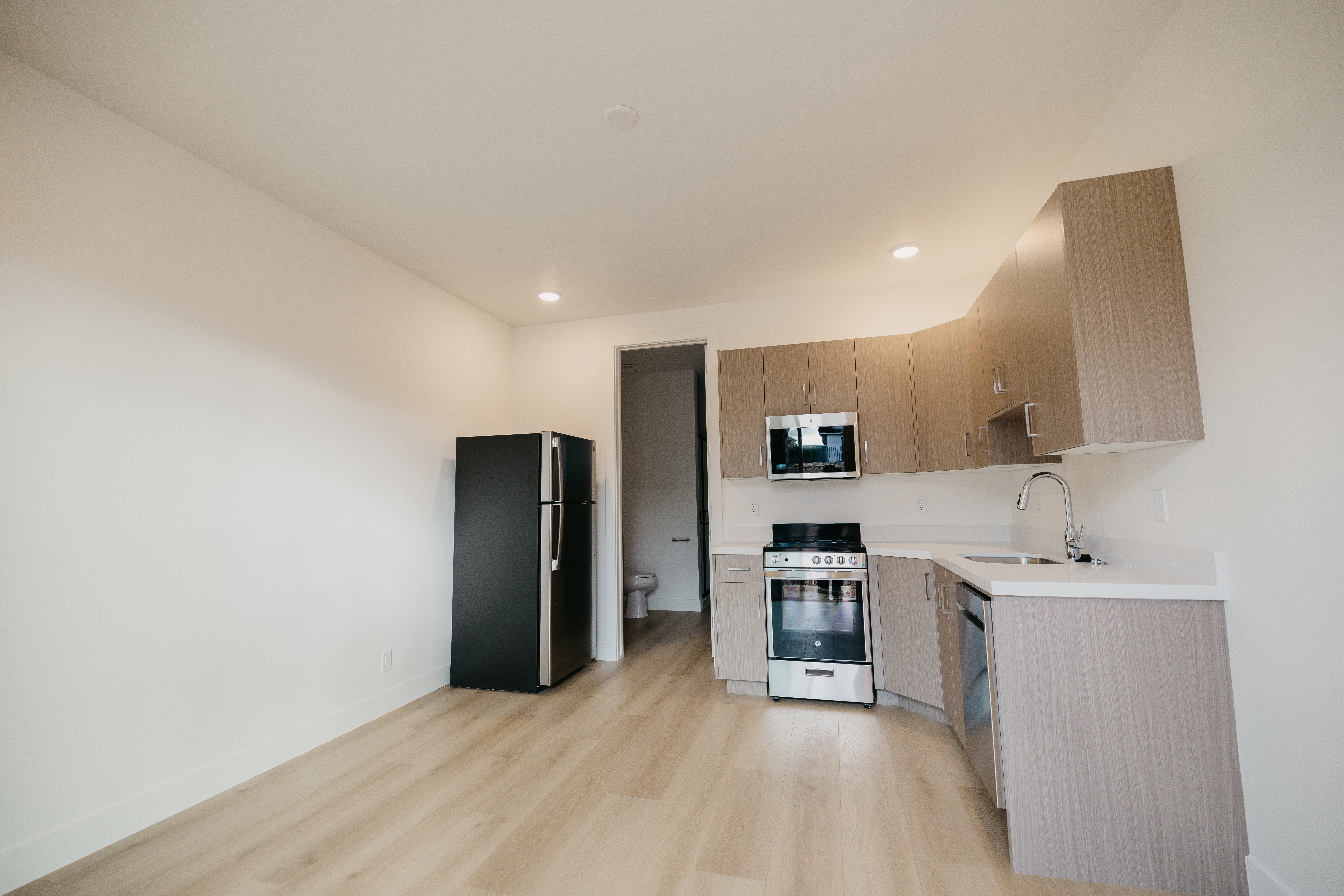 Kitchen featuring light countertops, stainless steel appliances, light wood-type flooring, modern cabinets, and recessed lighting