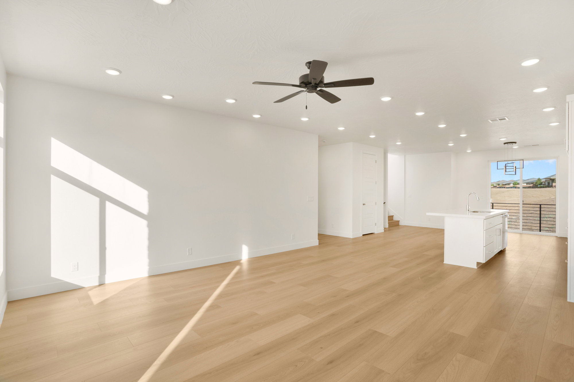 Open-concept living space with light wood-finish flooring, recessed lighting, and a ceiling fan