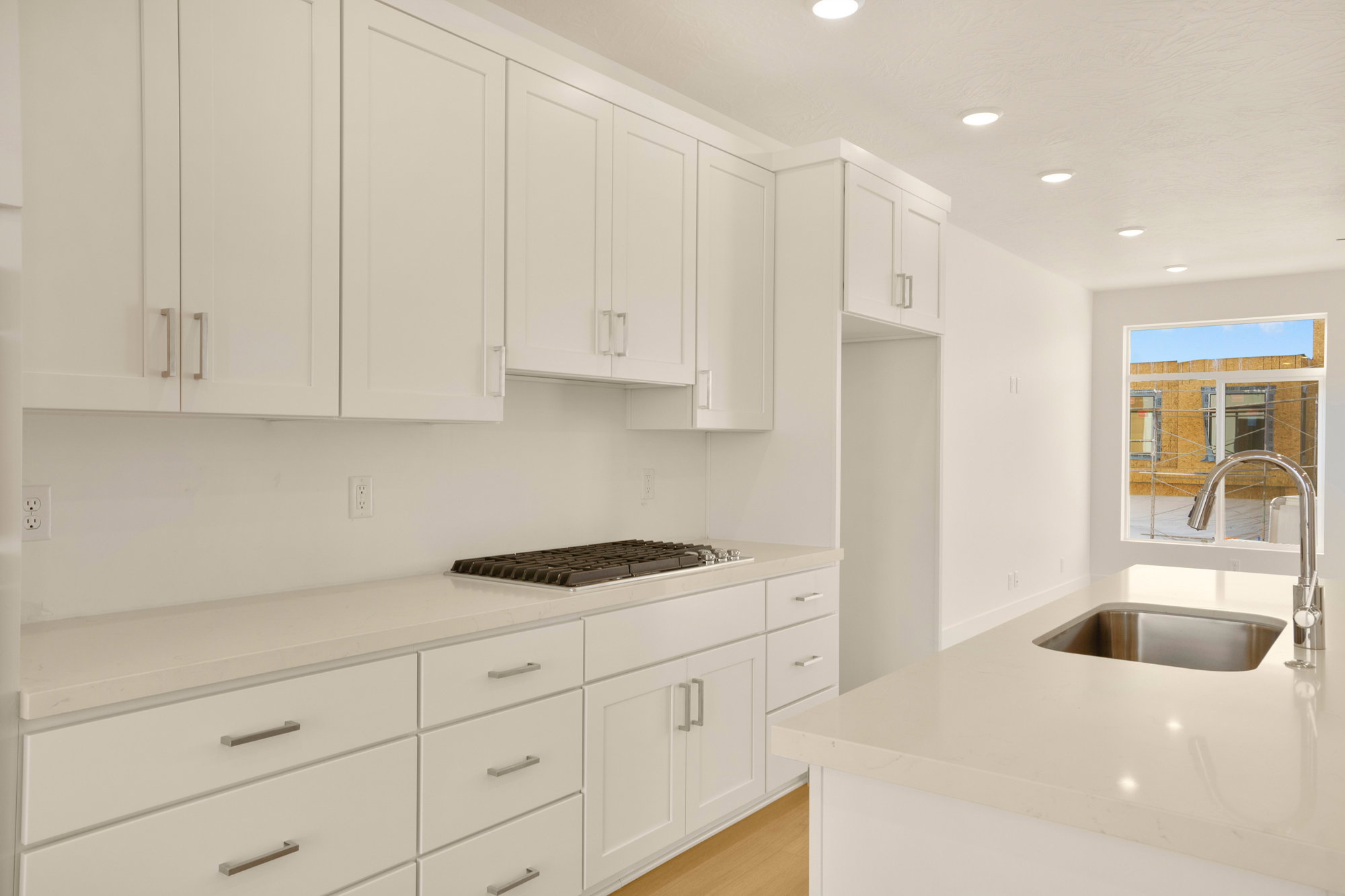 Bright kitchen featuring white shaker cabinetry, light countertops, recessed lighting, a gas cooktop, and a stainless steel sink with a gooseneck faucet