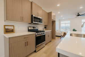 Kitchen featuring stainless steel appliances, light wood-type flooring, recessed lighting, modern cabinets, and light stone countertops