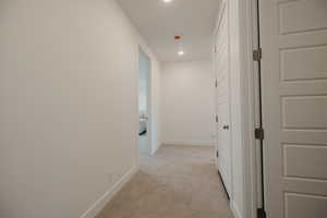 Hallway featuring light colored carpet and recessed lighting