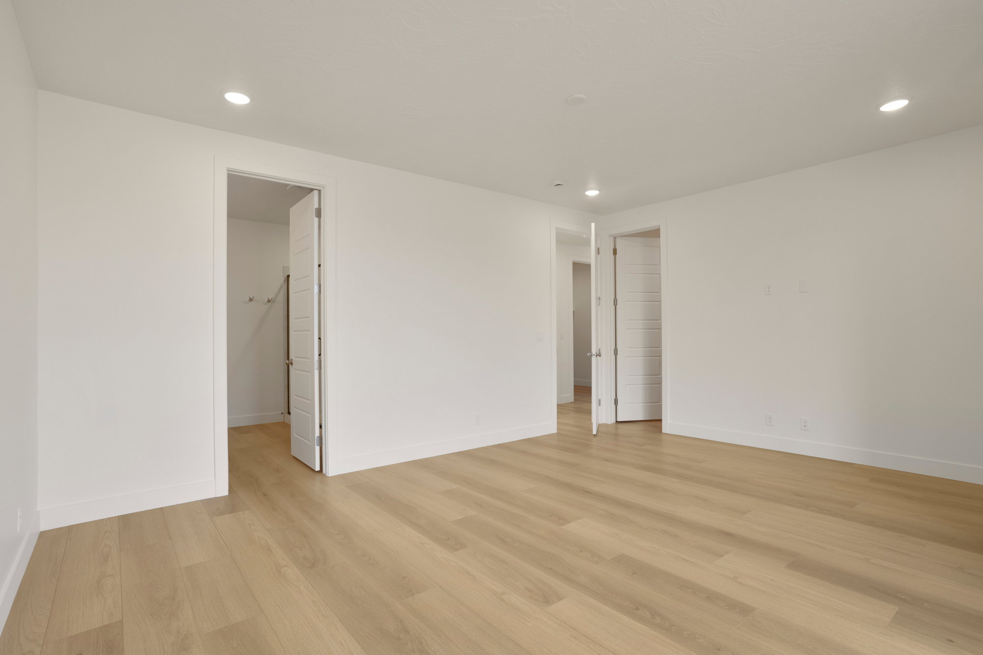 Spacious room featuring light wood-finish flooring and recessed lighting