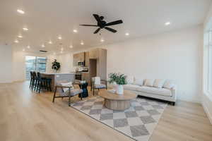 Living area with light wood-style flooring, ceiling fan, and recessed lighting