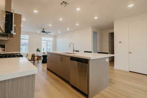 Kitchen with recessed lighting, an island with sink, light wood-style floors, stainless steel dishwasher, and modern cabinets