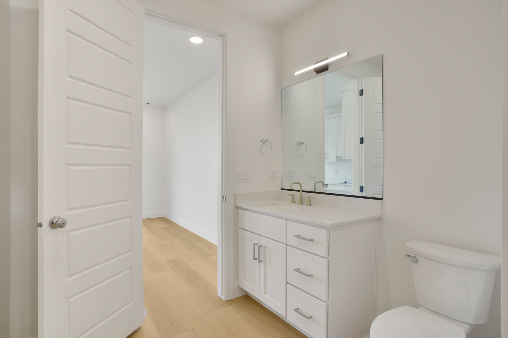 Bathroom featuring a white vanity with an integrated sink, brushed nickel faucet, and a large wall-mounted mirror with linear lighting