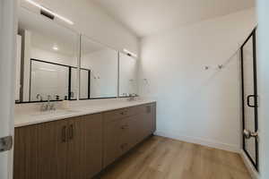 Bathroom with double vanity, a shower stall, and light wood finished floors