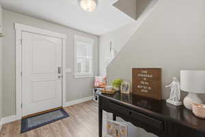 Foyer entrance with light wood-style flooring and baseboards