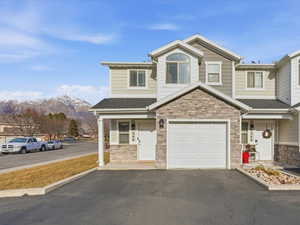 View of front of home featuring stone siding, driveway, a garage, and a mountain view