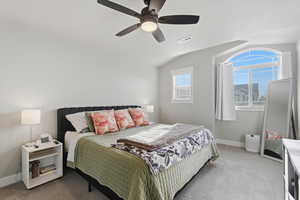 Bedroom with light colored carpet, a ceiling fan, and vaulted ceiling