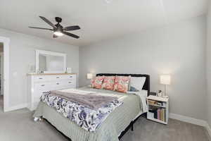 Bedroom with light colored carpet and a ceiling fan