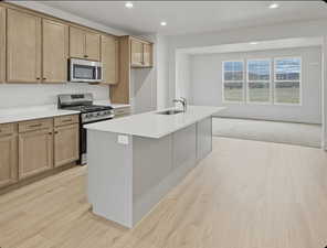 Two tone kitchen with stainless steel appliances, recessed lighting, a kitchen island with sink, light wood finished floors, and light stone counters