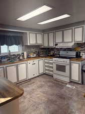 Kitchen with wooden counters, white cabinets, white appliances, and backsplash