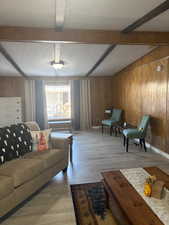 Living room with wood finished floors, wooden walls, and a textured ceiling