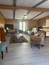 Living area with wooden walls, light wood finished floors, and a textured ceiling